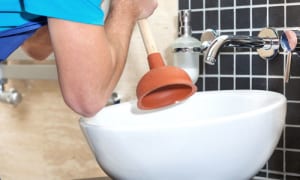 A man uses a pump to drain a sink.