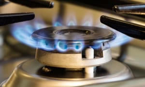 Gas stove with blue flames burning, connected to a natural gas line installation.